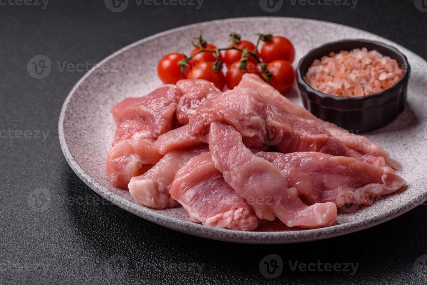 A pieces of raw fresh pork on a wooden cutting board with spices and herbs photo