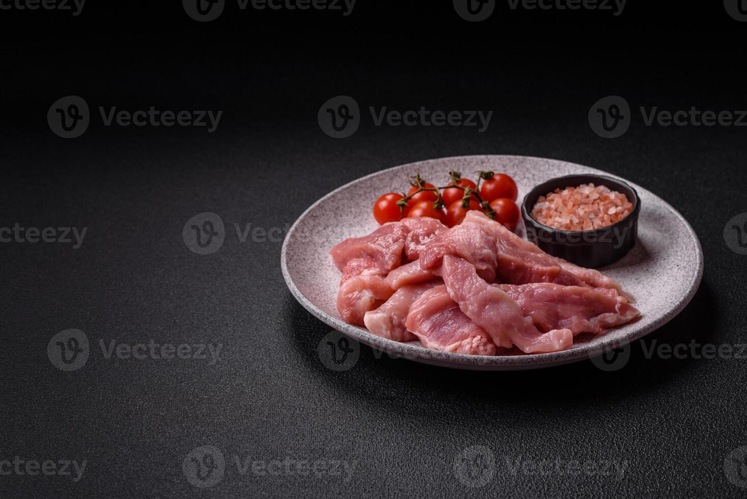 A pieces of raw fresh pork on a wooden cutting board with spices and herbs photo