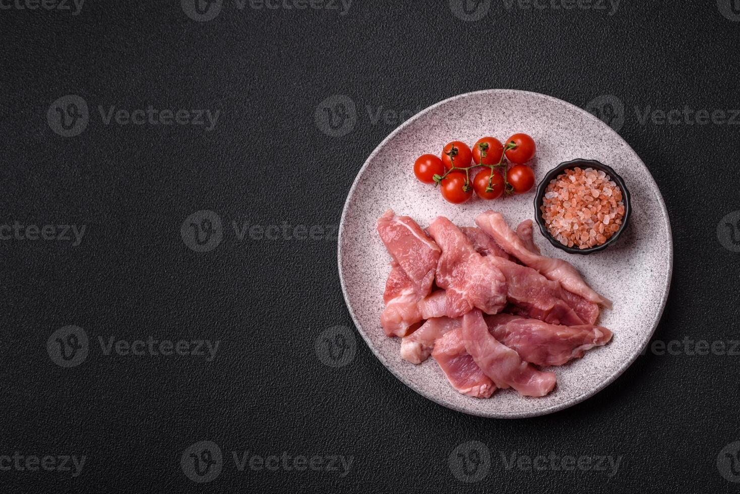 A pieces of raw fresh pork on a wooden cutting board with spices and herbs photo