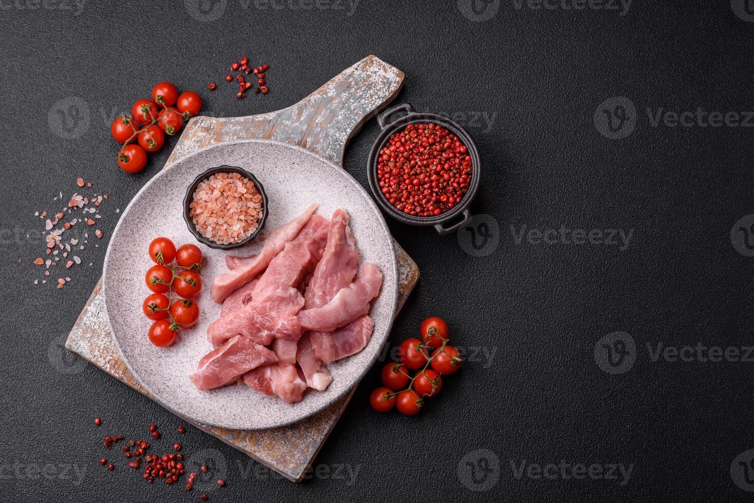 A pieces of raw fresh pork on a wooden cutting board with spices and herbs photo