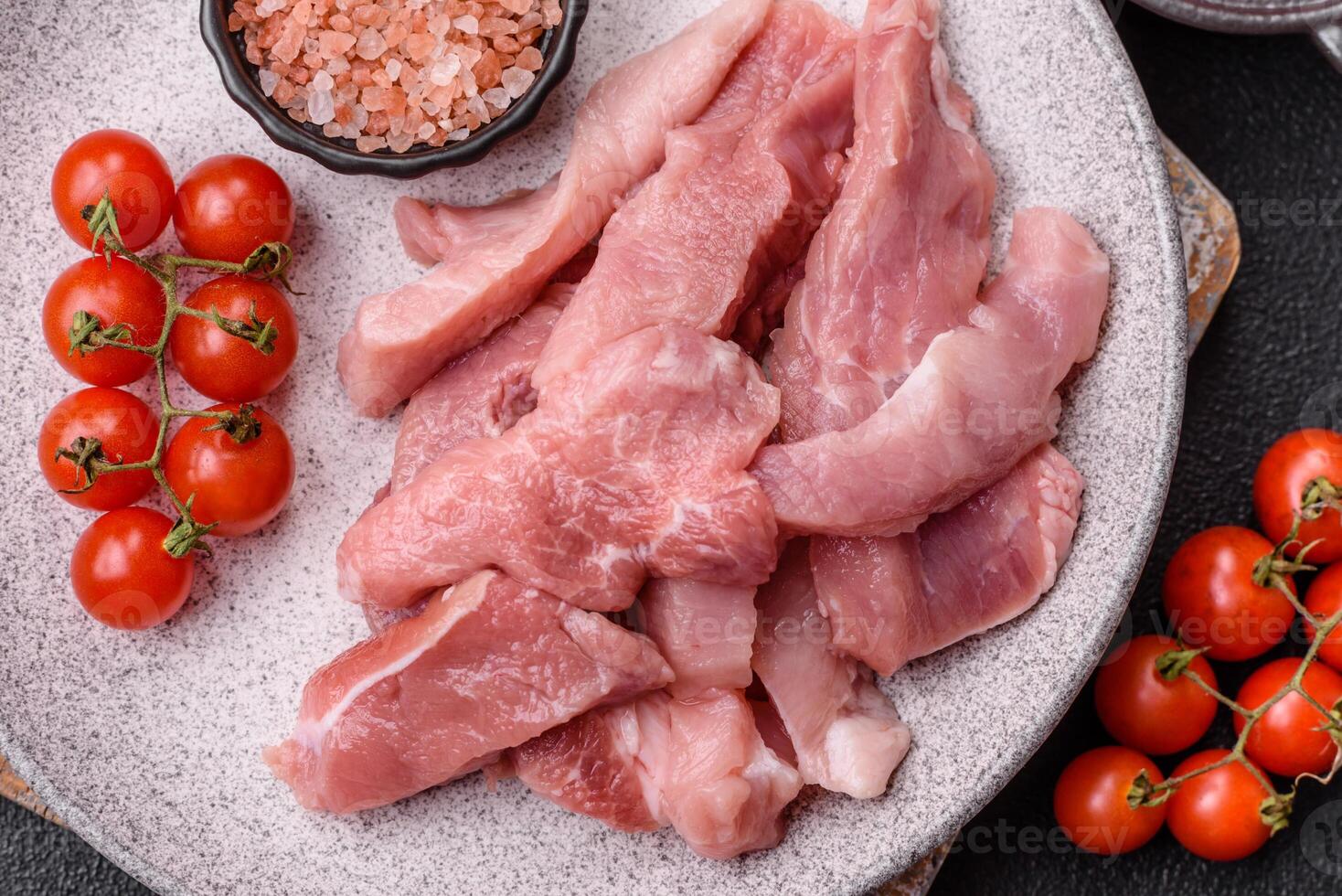 A pieces of raw fresh pork on a wooden cutting board with spices and herbs photo