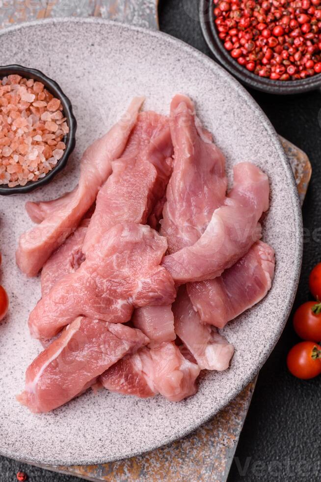 A pieces of raw fresh pork on a wooden cutting board with spices and herbs photo