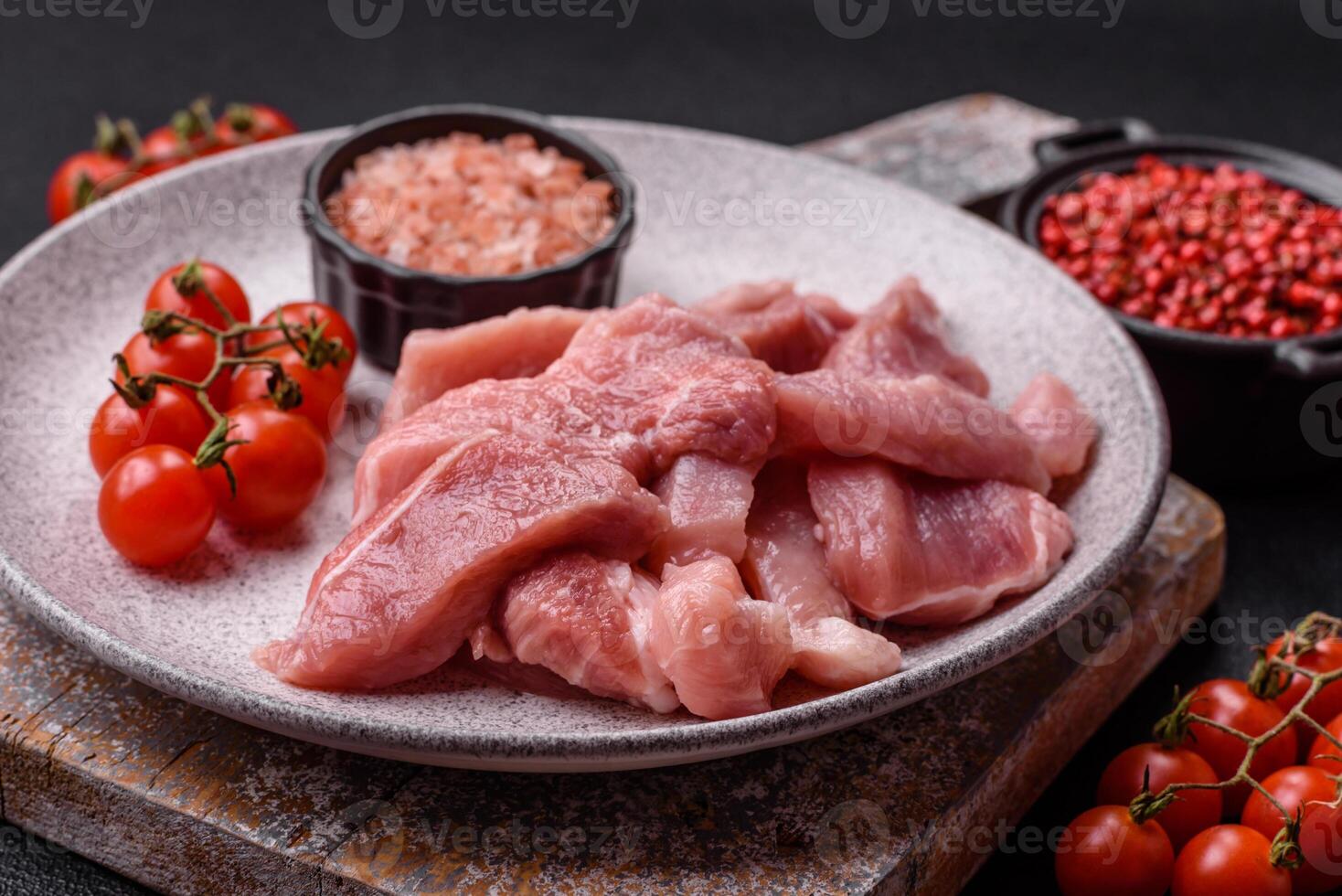 A pieces of raw fresh pork on a wooden cutting board with spices and herbs photo