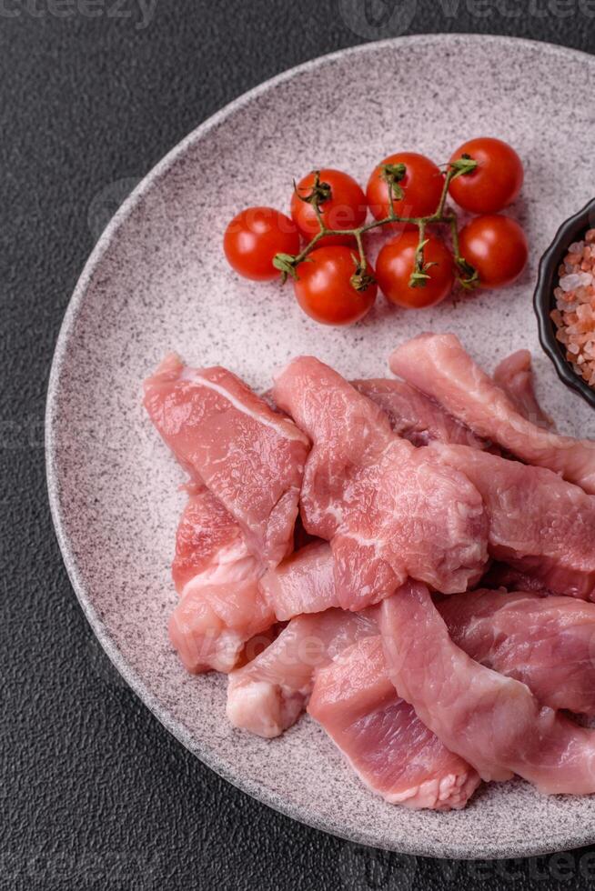 A pieces of raw fresh pork on a wooden cutting board with spices and herbs photo