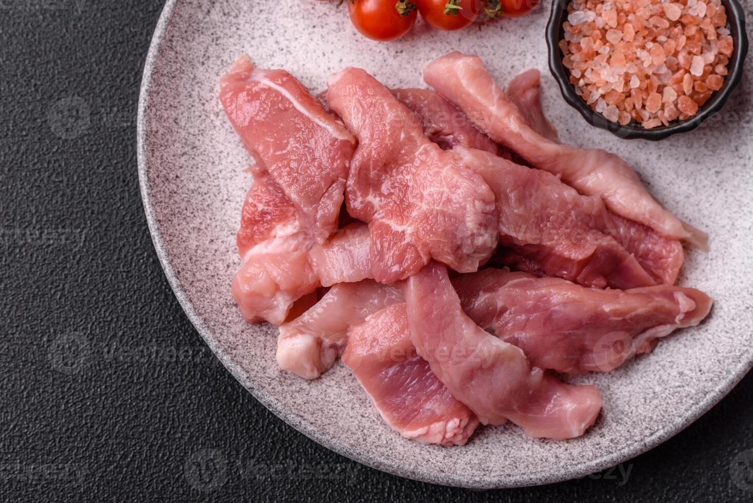 A pieces of raw fresh pork on a wooden cutting board with spices and herbs photo