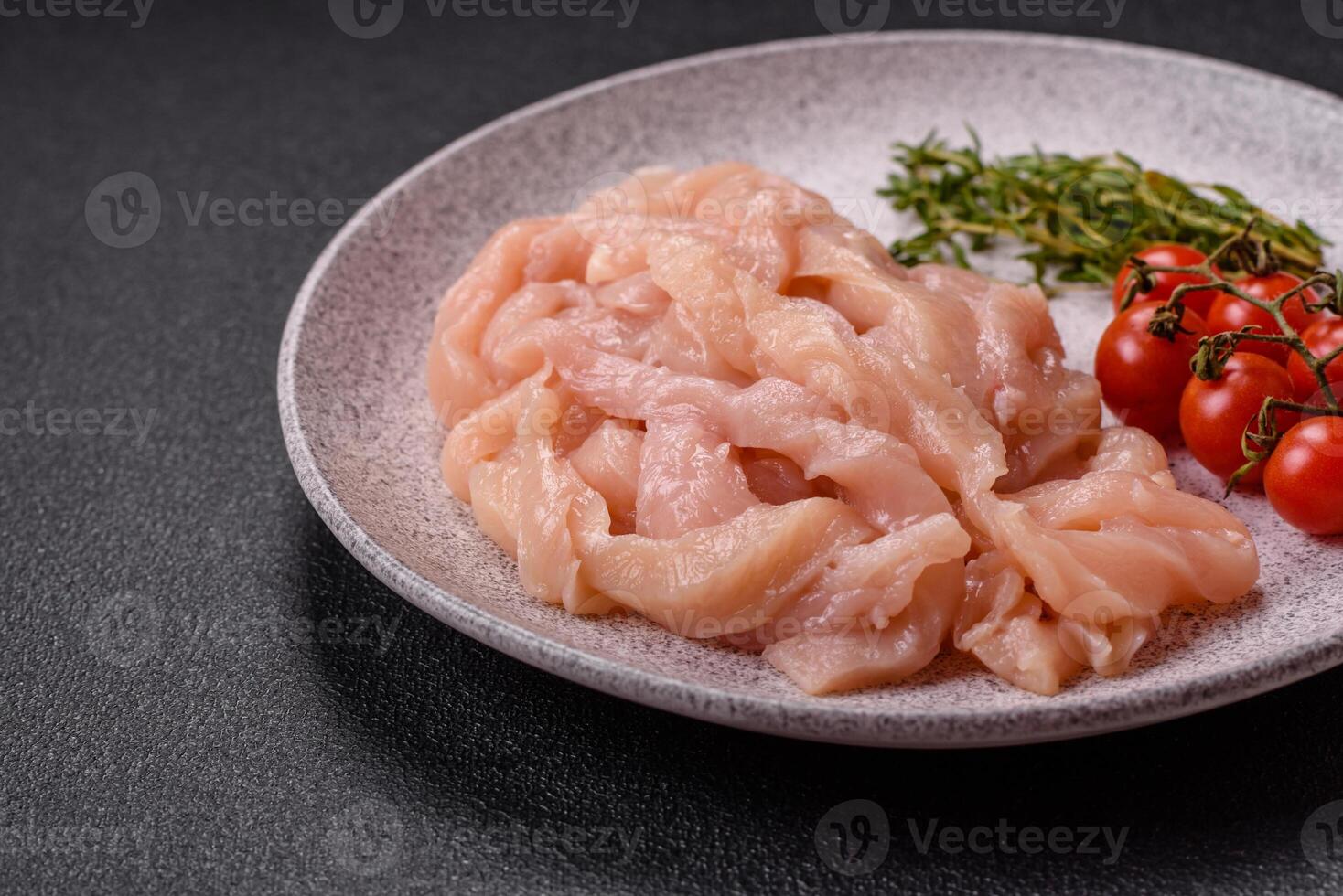 Raw chicken fillet cut into strips with spices and herbs photo