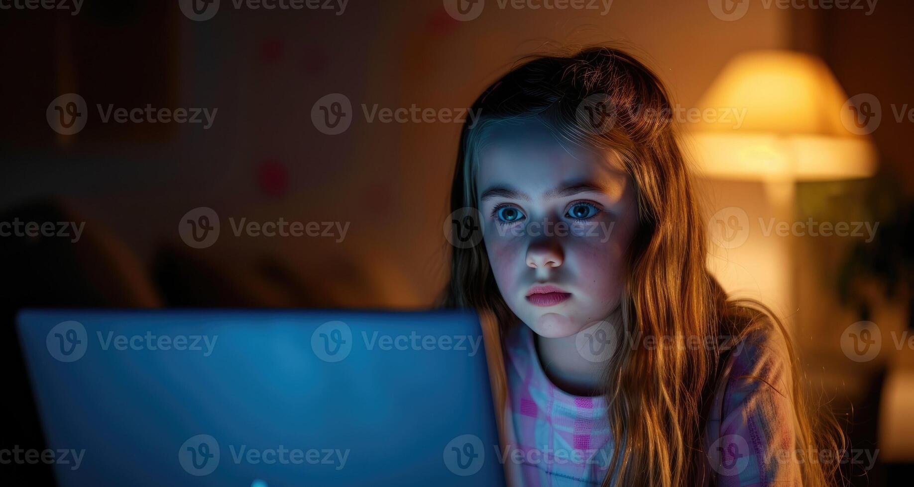 A young girl with her laptop open looking scared and unsure of how to respond to threatening messages from an unknown online bully. photo