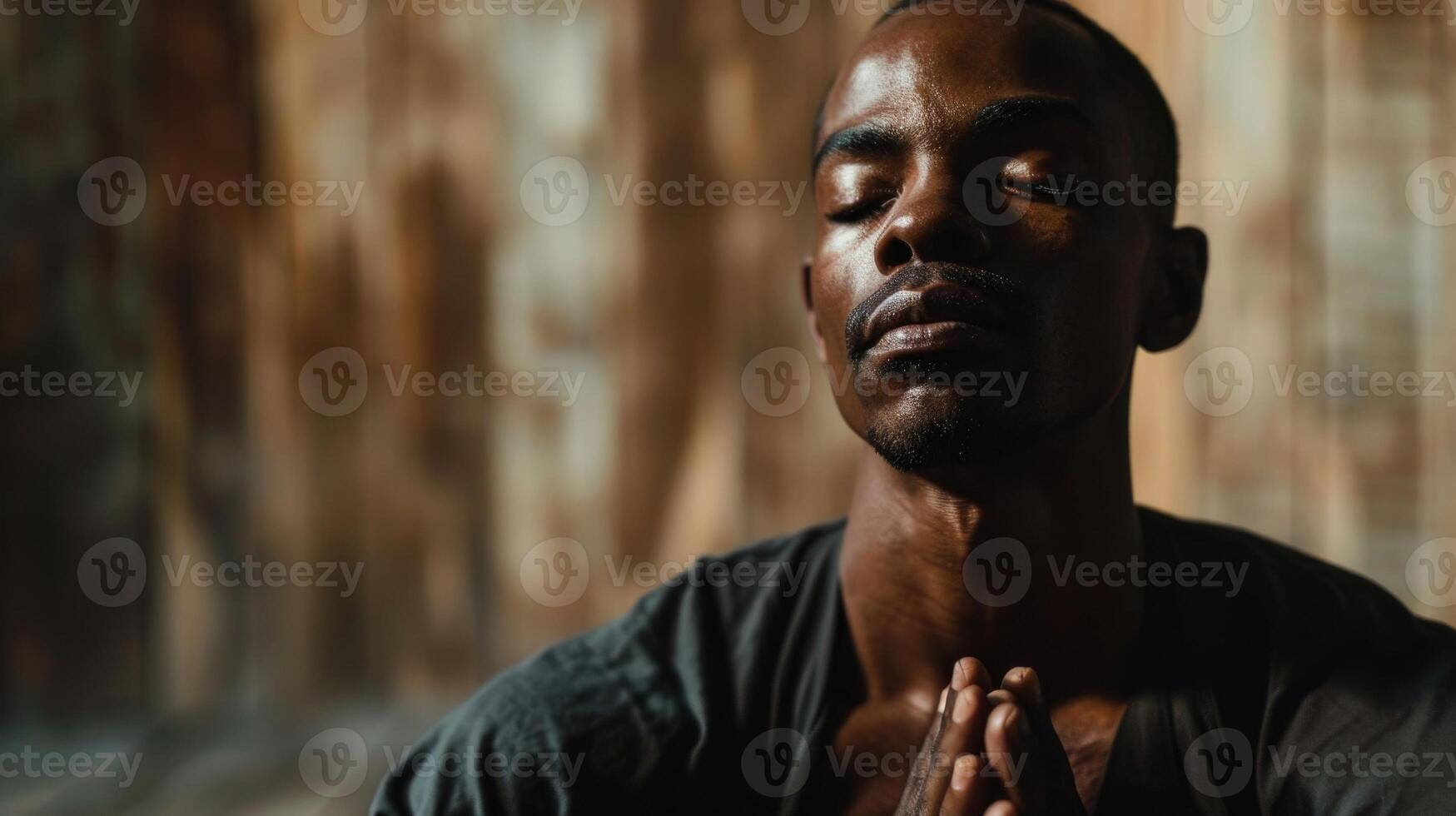 A man sitting with his eyes closed and his hands resting on his knees, a serene and peaceful expression on his face as he practices deep and intentional breaths. photo