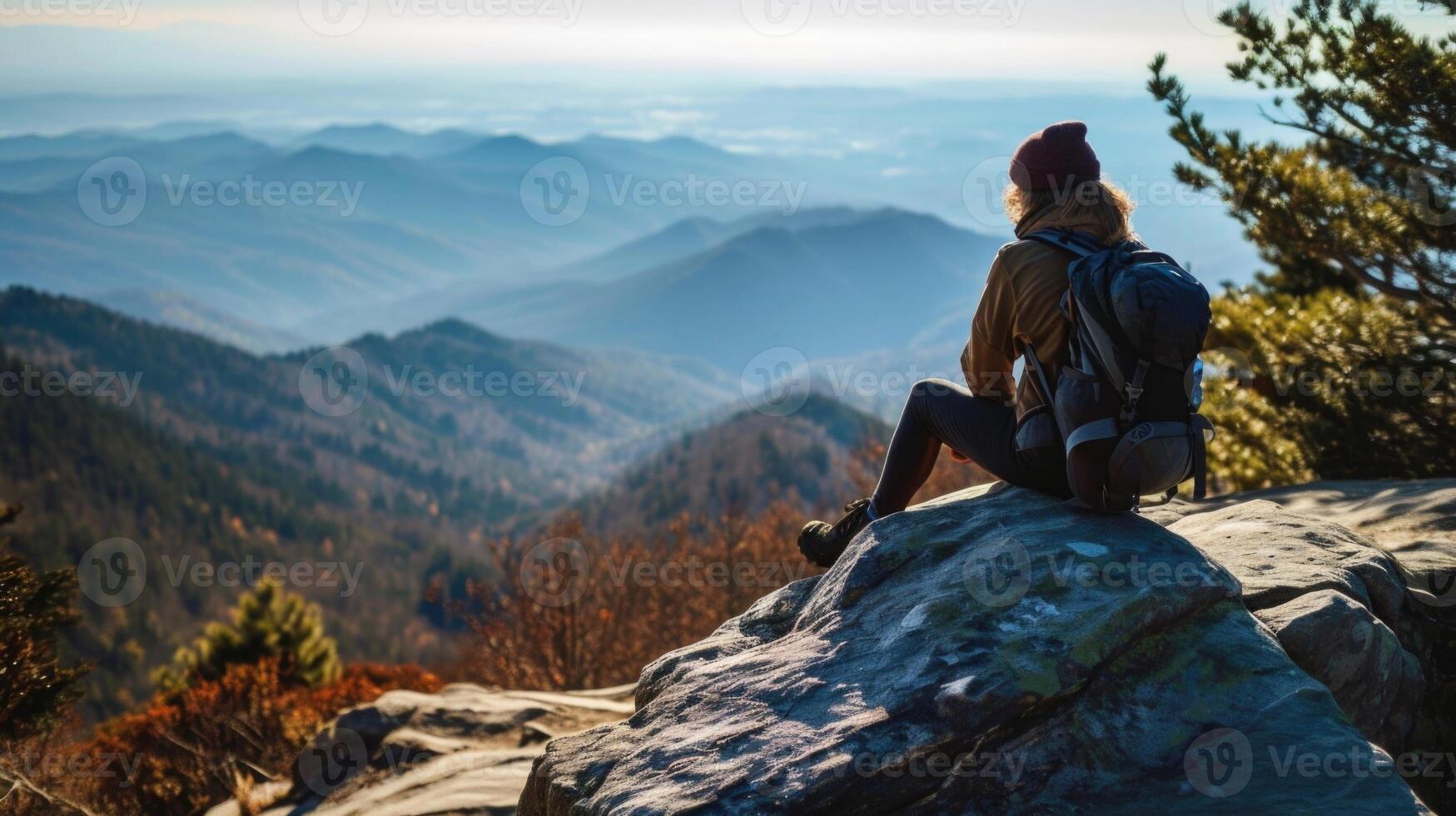 A hiker sitting on a boulder, gazing out at the breathtaking views and practicing gratitude. photo