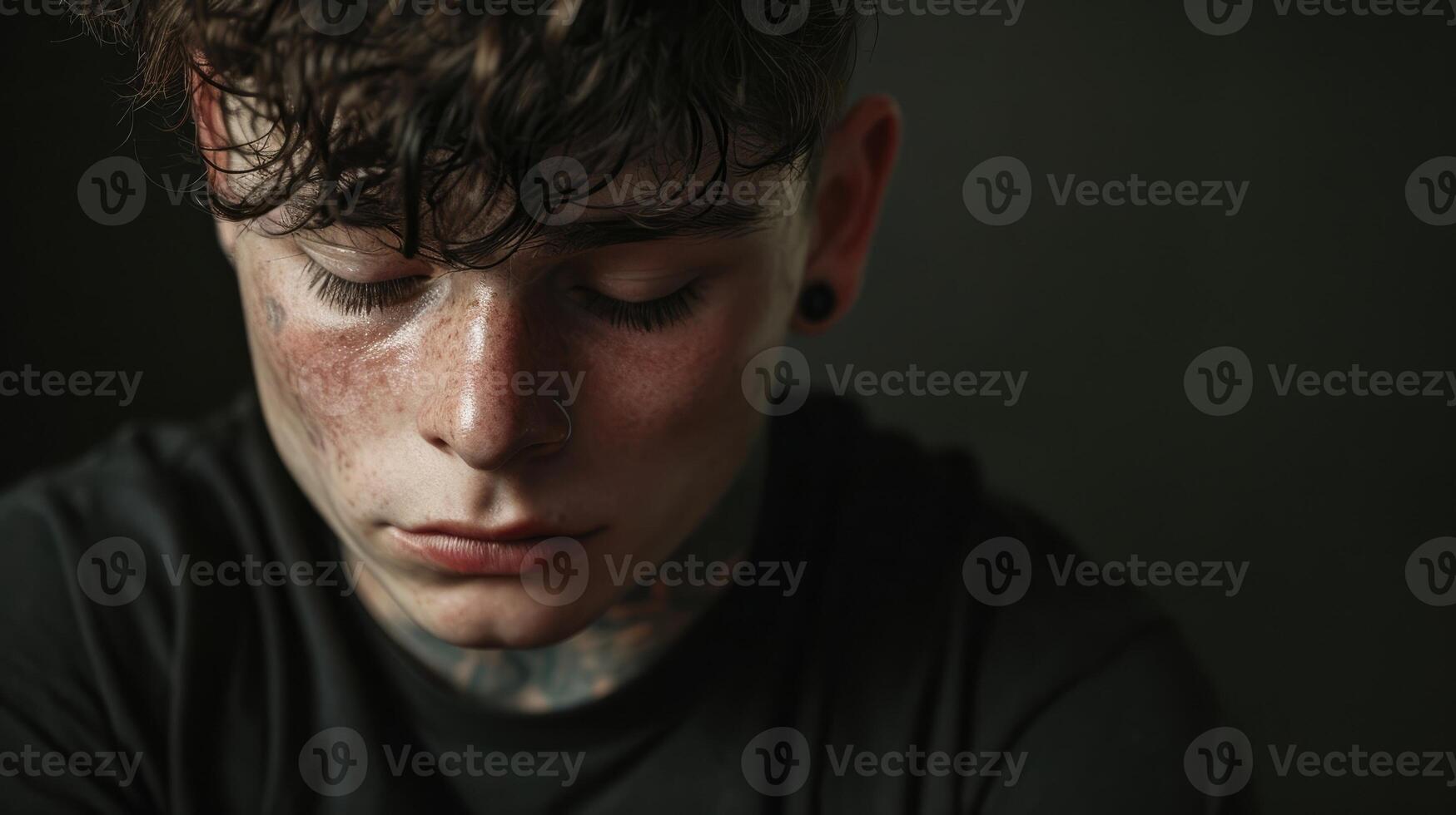 A teenage boy with a tattoo of a loved ones name on his arm his eyes closed in a moment of grief photo