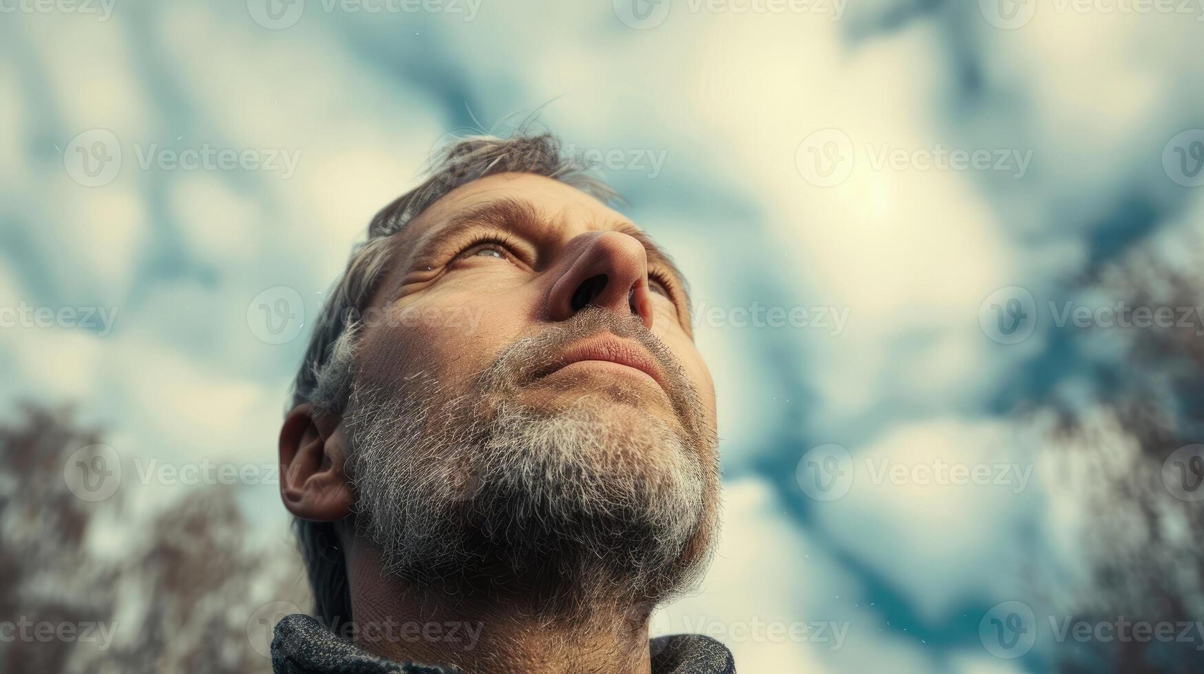 A middleaged man his face turned upwards towards the sky a look of wonder and awe on his face as he experiences a profound spiritual realization photo