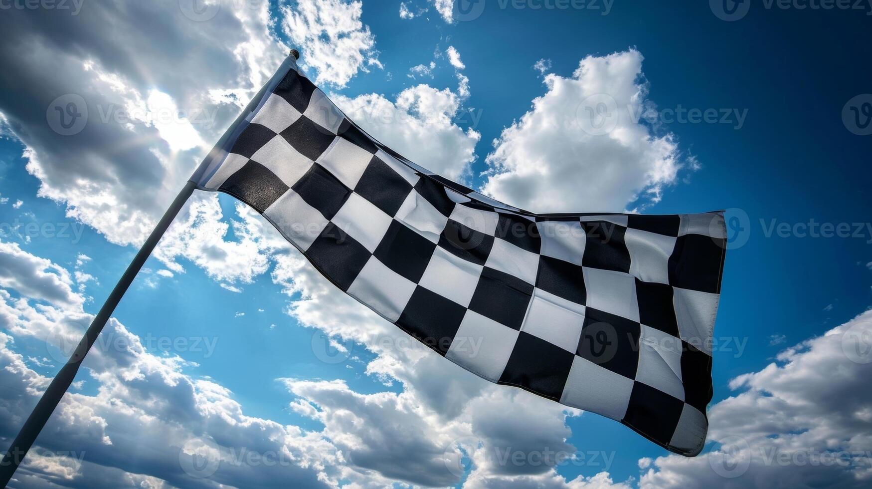 A closeup shot of the checkered flag being waved against a backdrop of billowing white clouds evoking a feeling of triumph and accomplishment photo