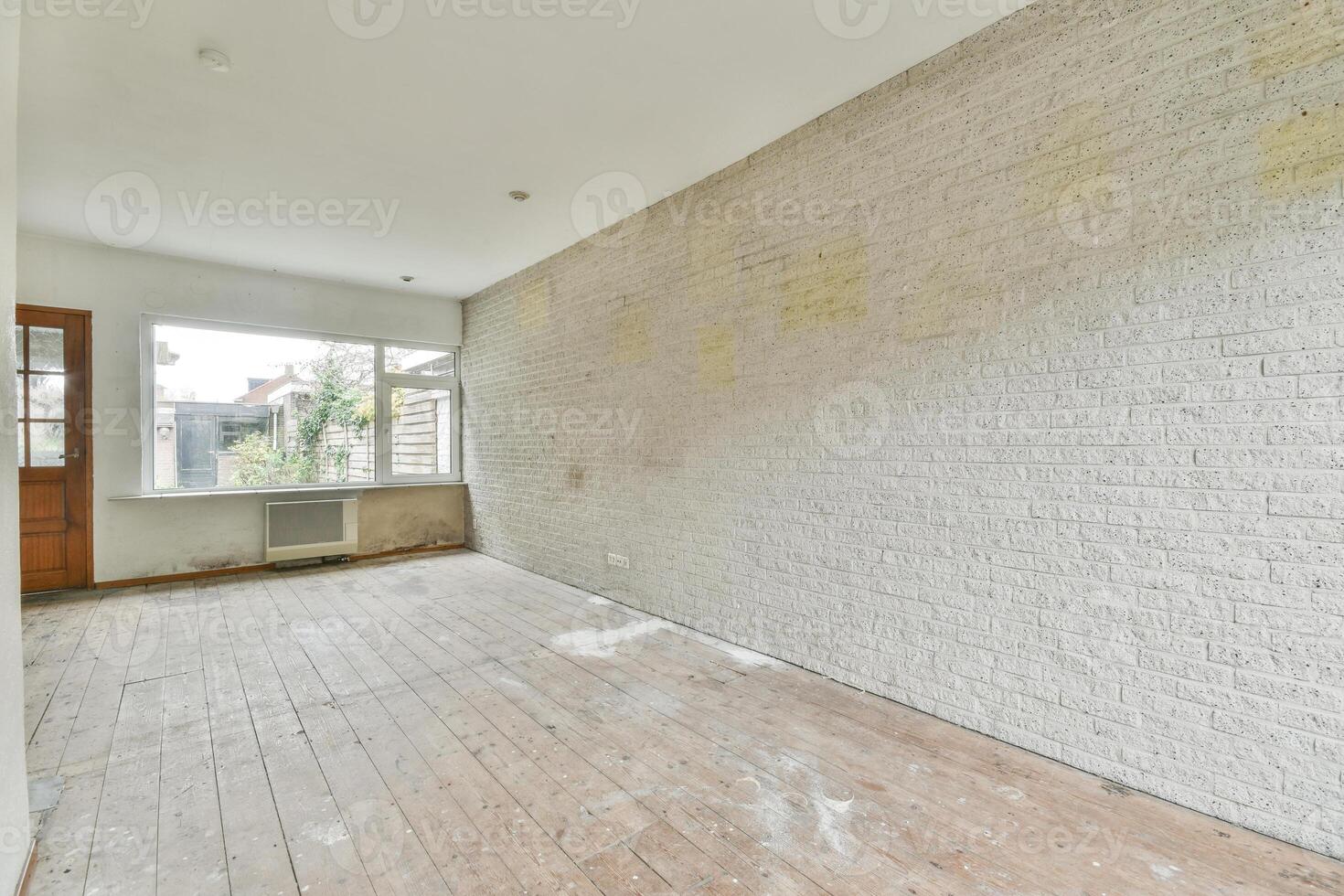 An empty room with a brick wall and wooden floors photo