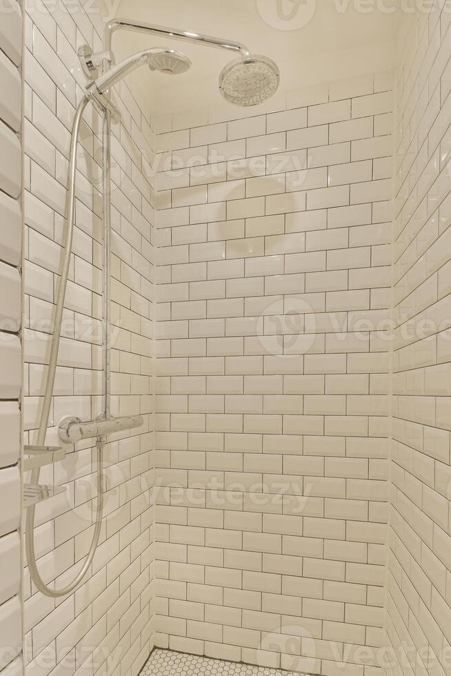 A shower with a white tile floor and a shower head photo