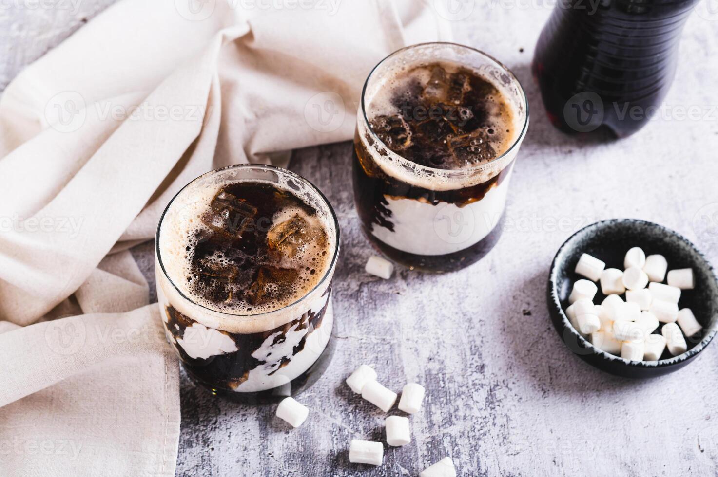 Trendy fluffy coke with marshmallow in glasses on the table photo