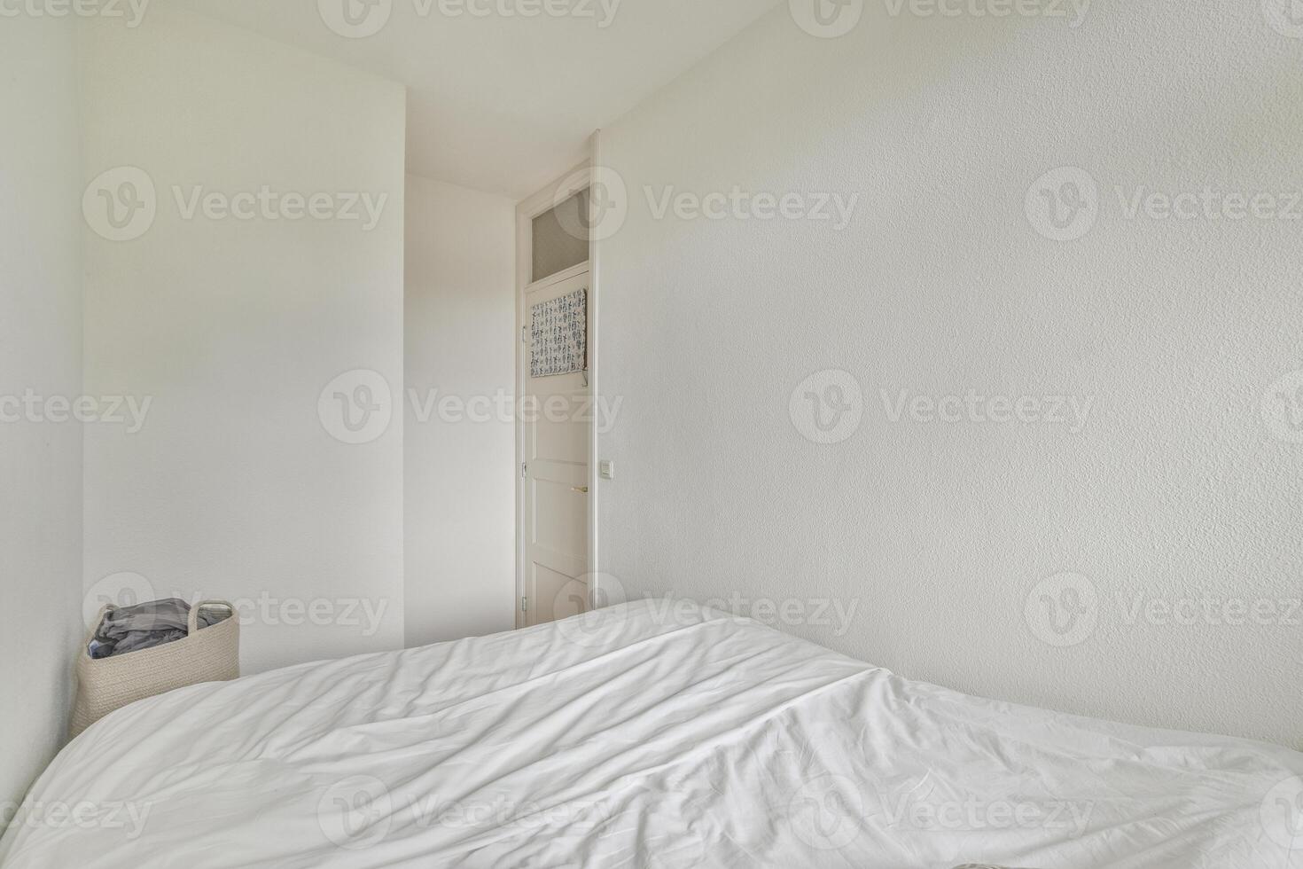 A white bedroom with a bed and a white wall photo