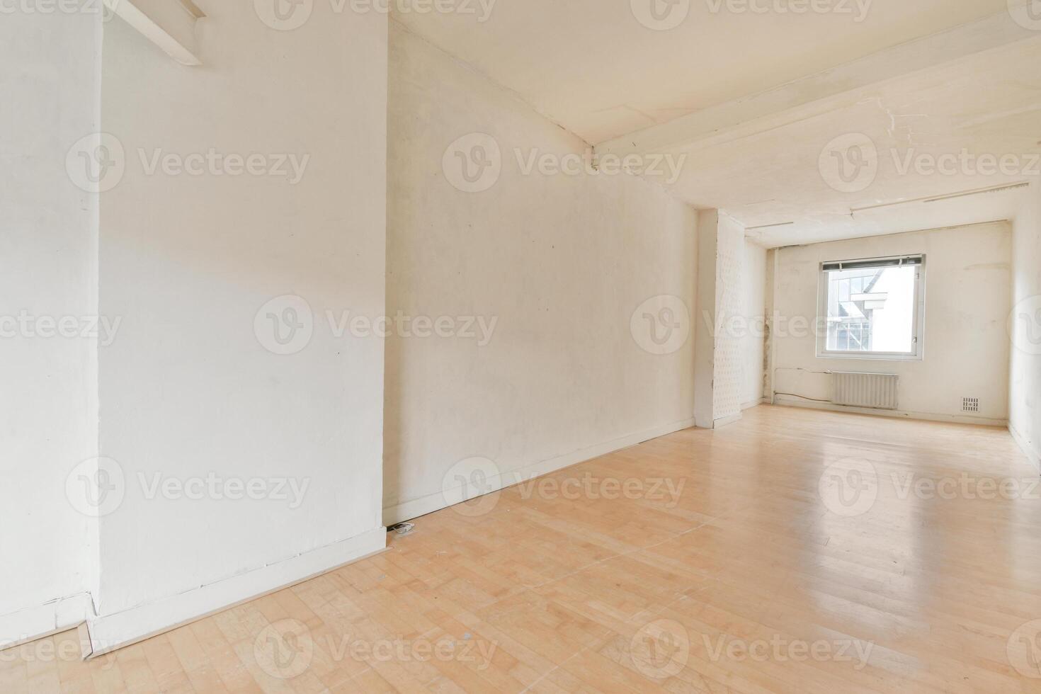 An empty room with a wooden floor and white walls photo