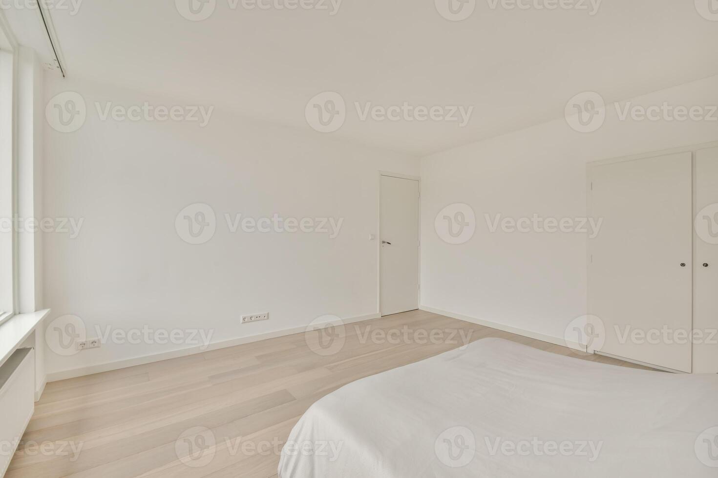 A bedroom with white walls and wooden floors photo