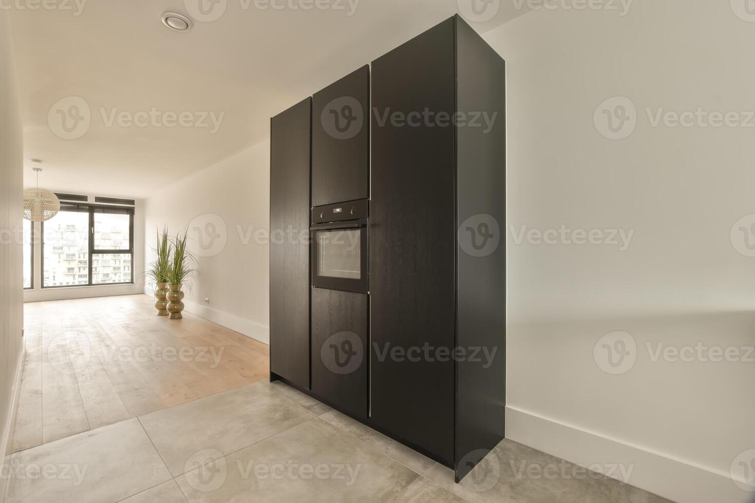 A black refrigerator in a hallway with a wooden floor photo