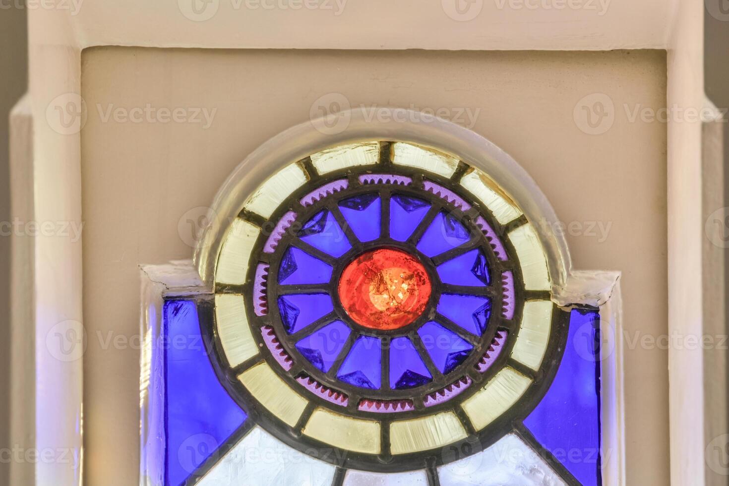 A stained glass window with a red sun in the center photo