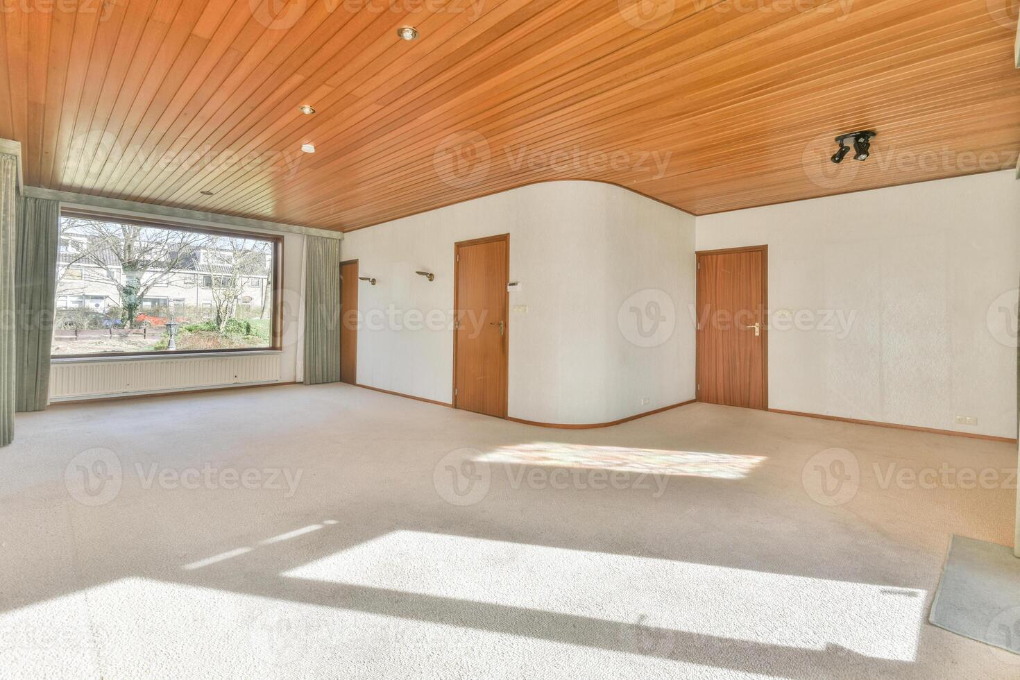 A large empty room with wood paneling and a window photo