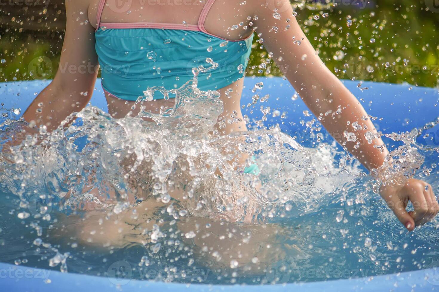Little girl playing in swimming pool outdoors at summer. photo