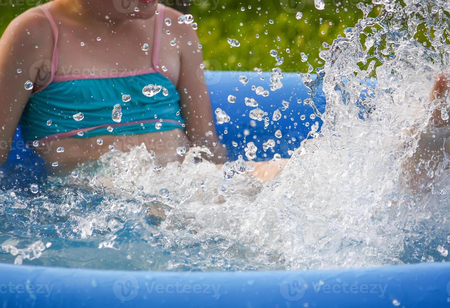 Little girl playing in swimming pool outdoors at summer. photo