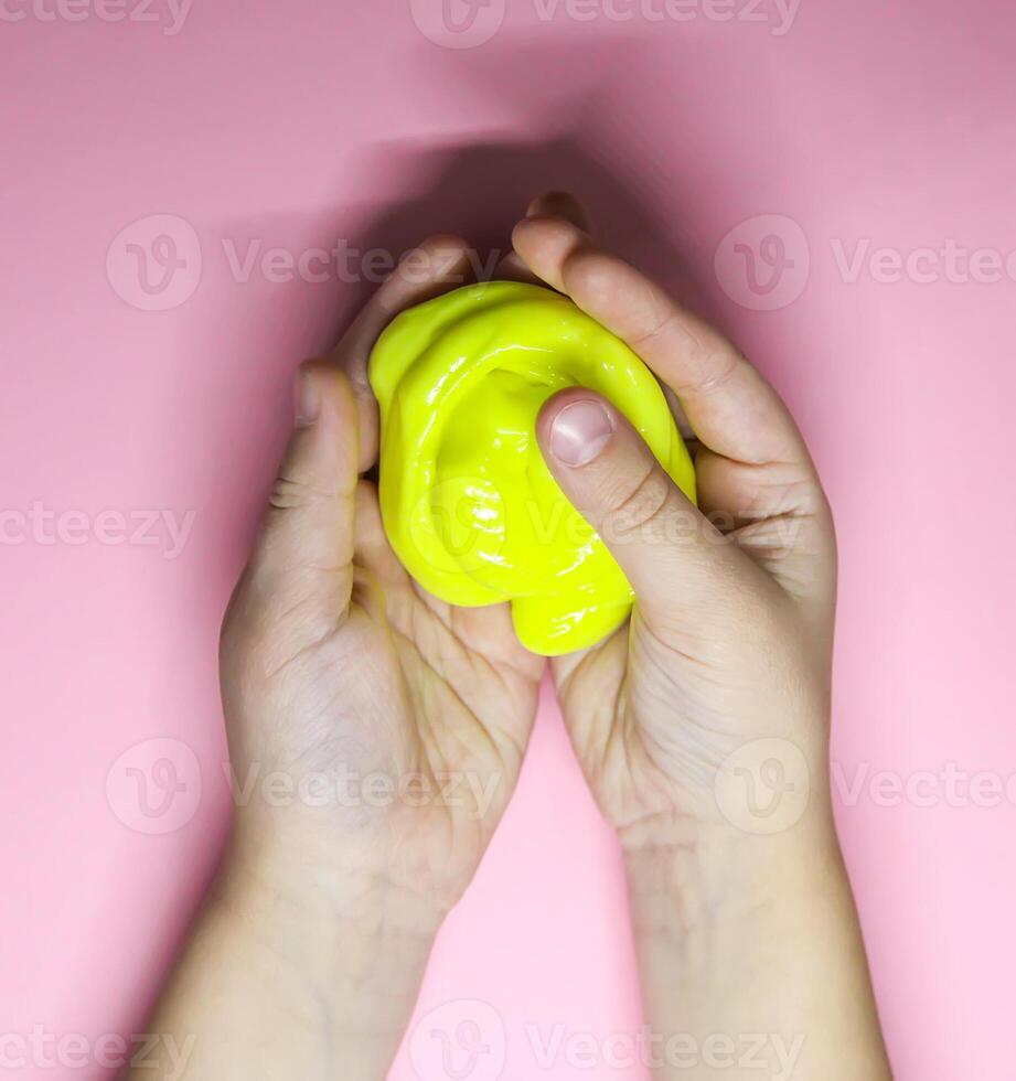 Girl playing with yellow slime in her hands. photo
