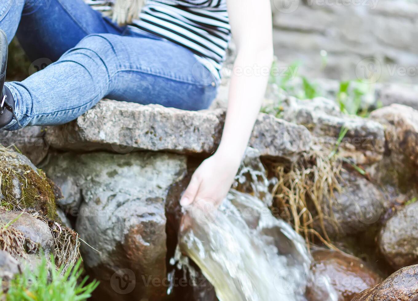 Woman hands in cold transparent water stream in supring park photo