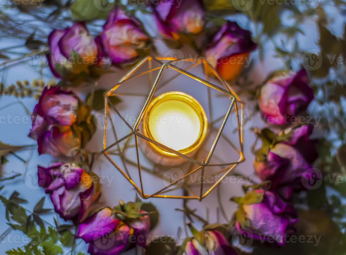 Dry rose flowers and burning candle in the metal candlestick. Decor for natural candles. photo