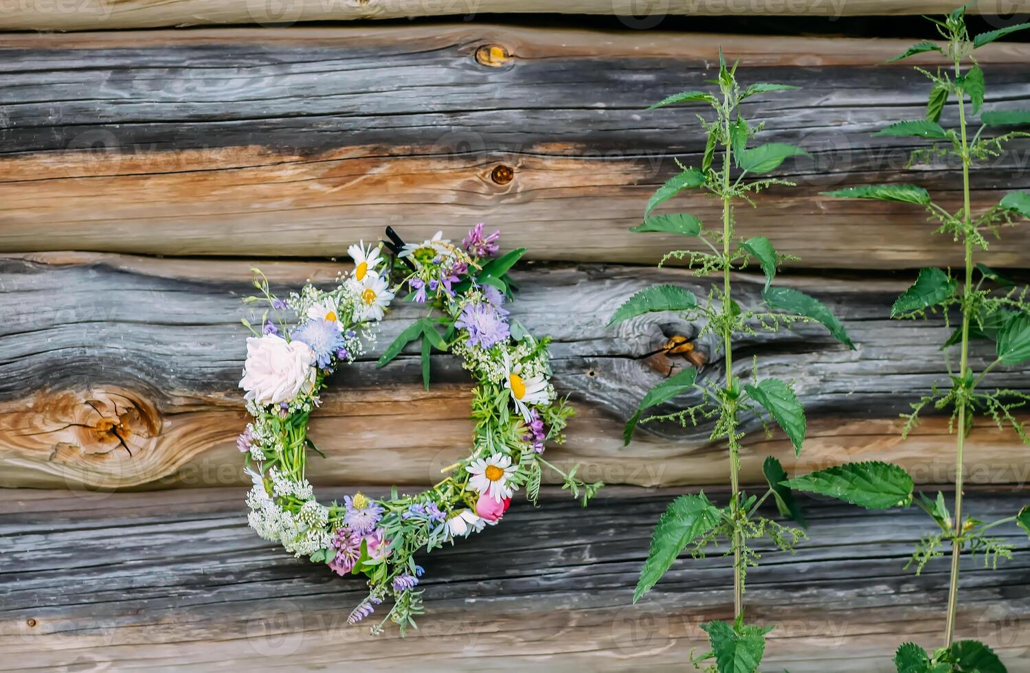 Wreath of wildflowers hanging on the weathered wooden wall. Floral decor in rustic style. photo