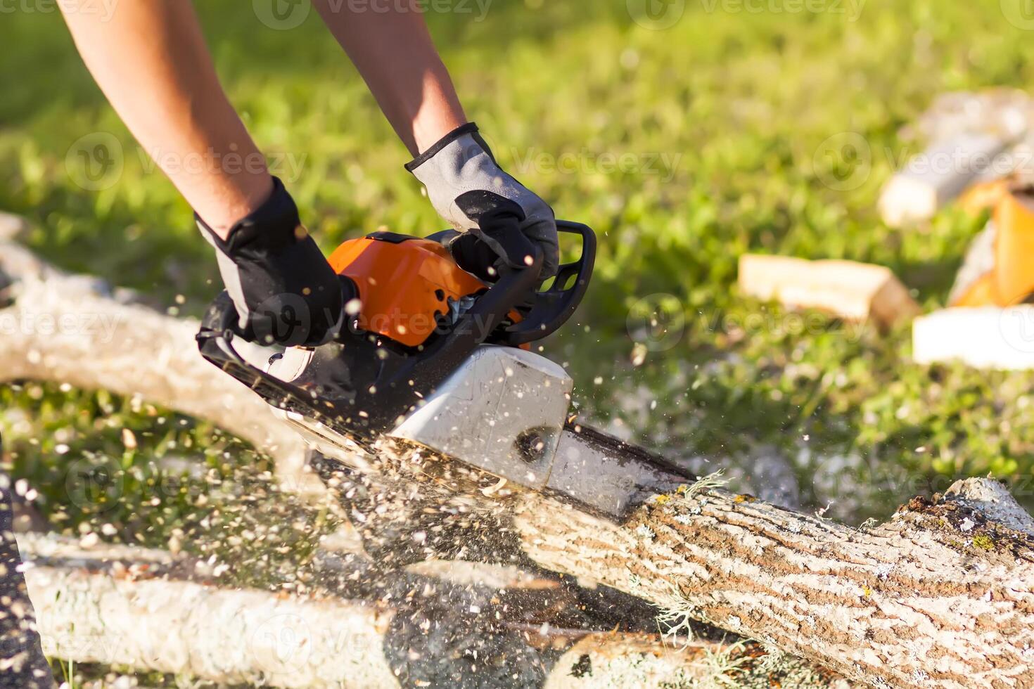 Hands of a man holding a chainsaw and saw logs. photo