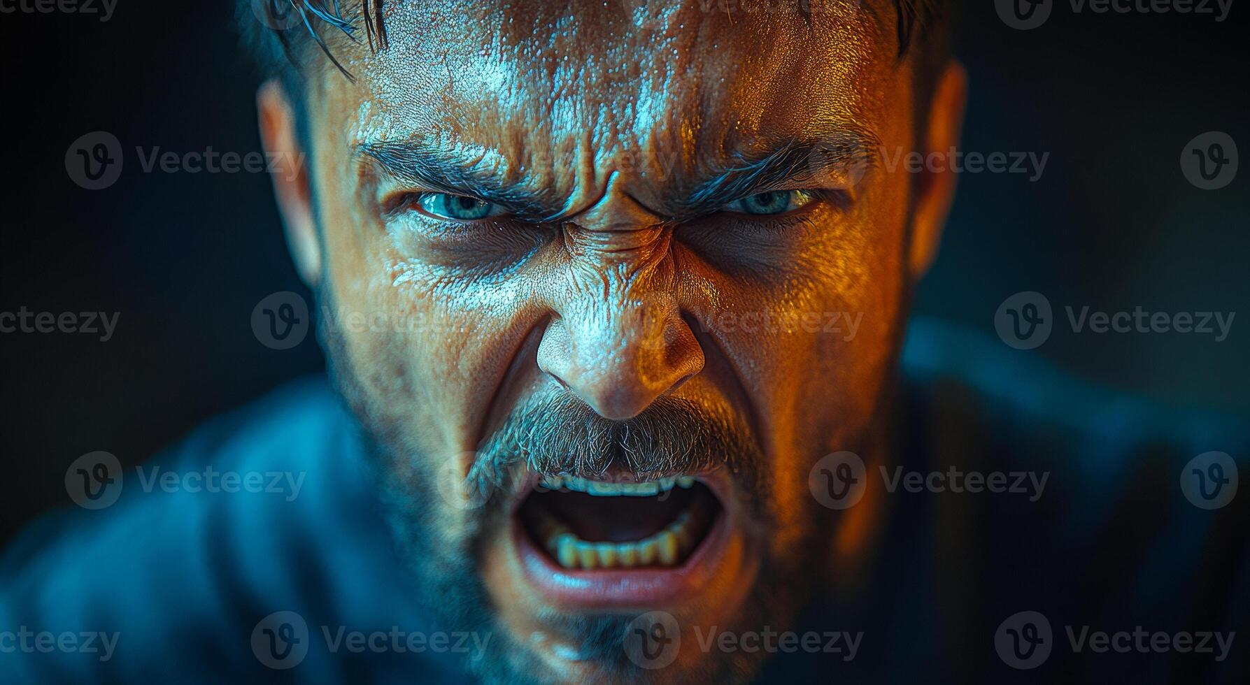 A man with a scowl on his face and his mouth open. He looks angry and is wearing a black shirt photo