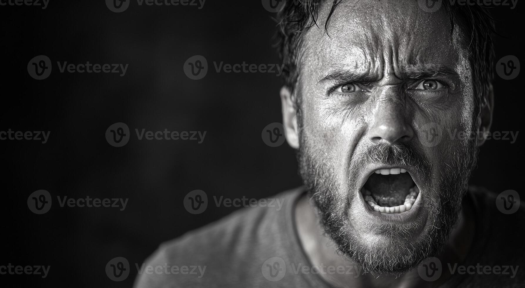 A man with a beard and a mouth open in a black and white photo. The man's expression is angry and he is yelling photo