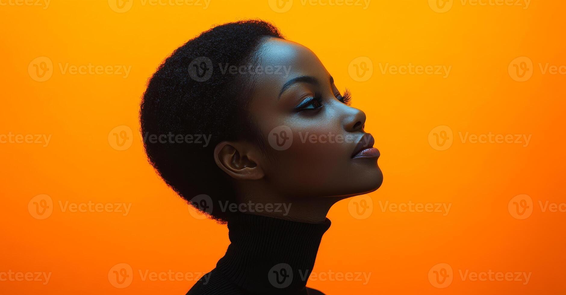 A woman with a short haircut and a black sweater is standing in front of an orange background. Concept of confidence and strength, as the woman's posture photo