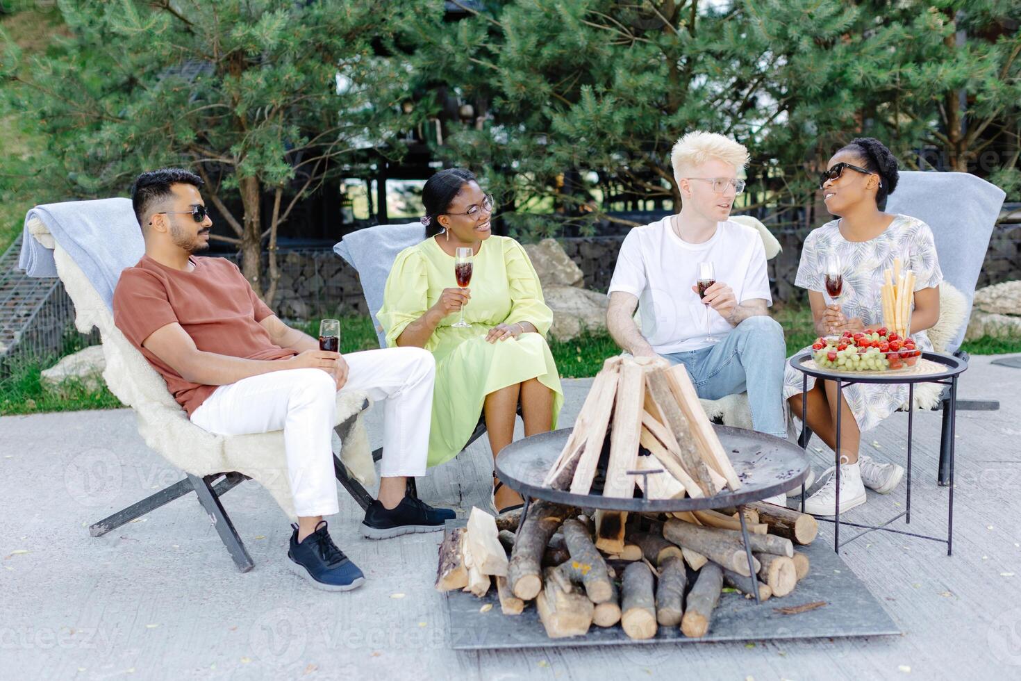 Friends celebrating outside, drinking wine and eating fruit on a picnic photo