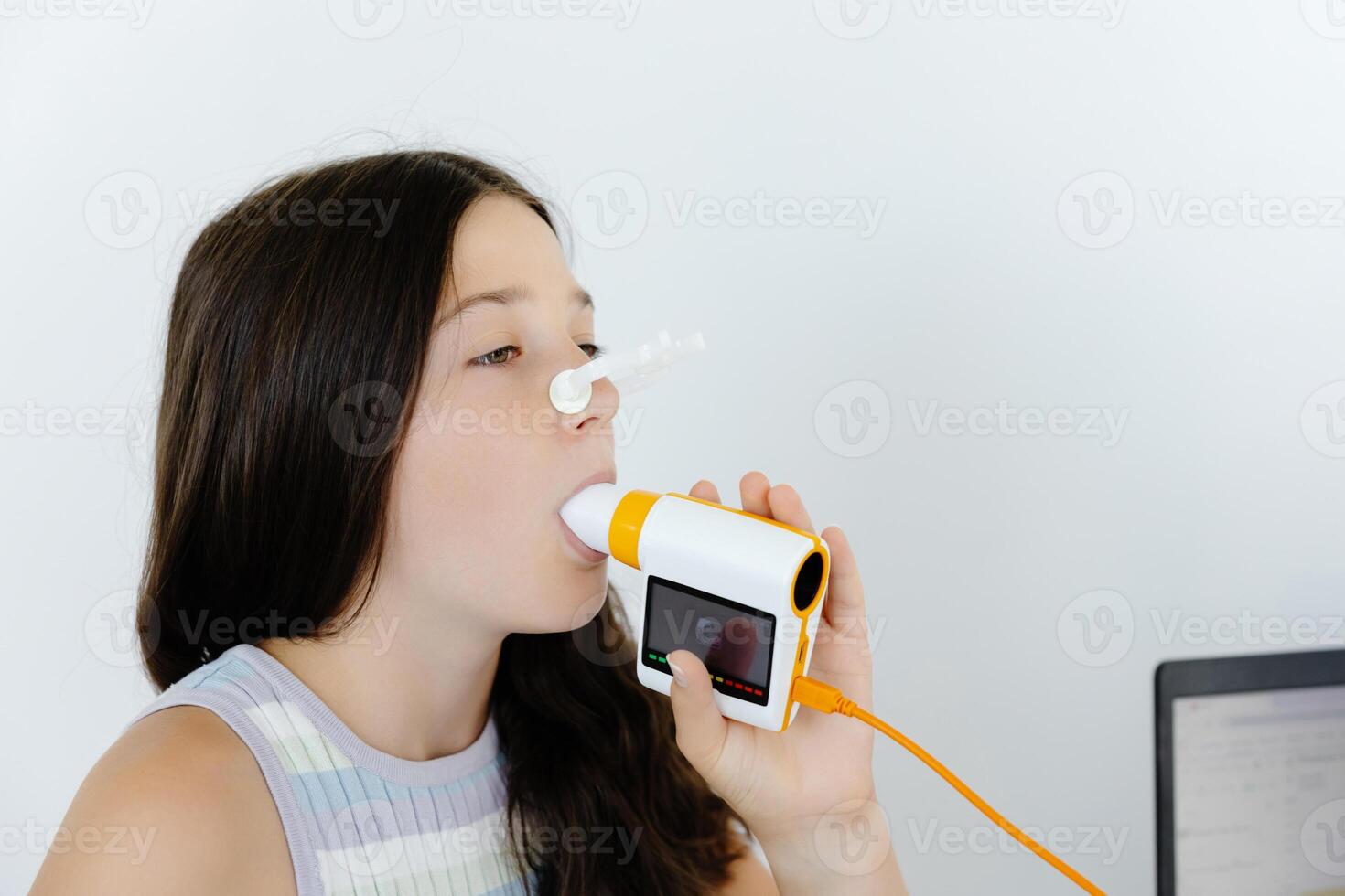 Girl testing breathing function by spirometry in doctors office. Diagnosis of respiratory function in pulmonary disease photo