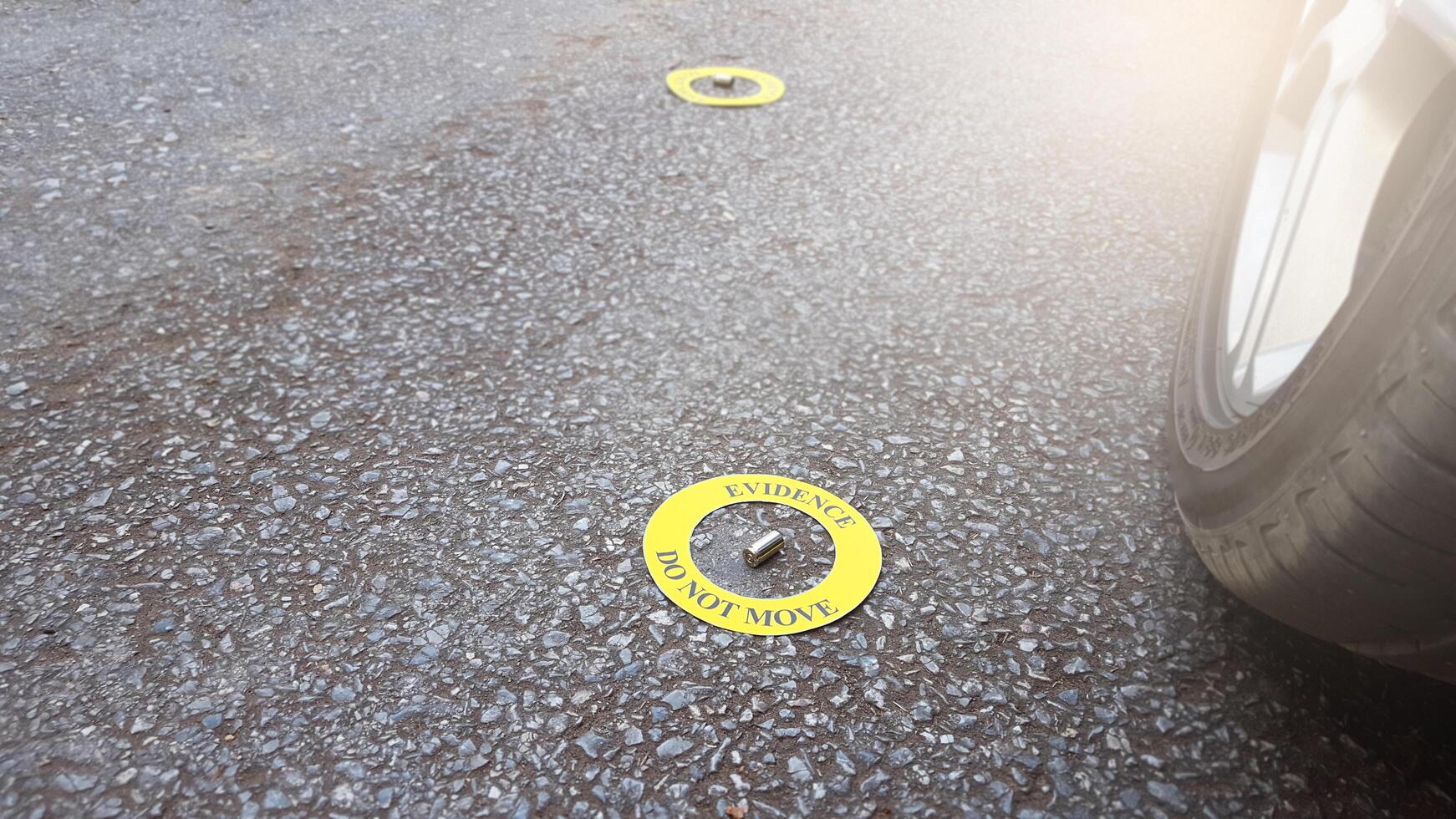 A spent bullet casing placed within a yellow circle, labeled with the text Evidence, Do Not Move, set against pavement background, concept of crime investigation. photo