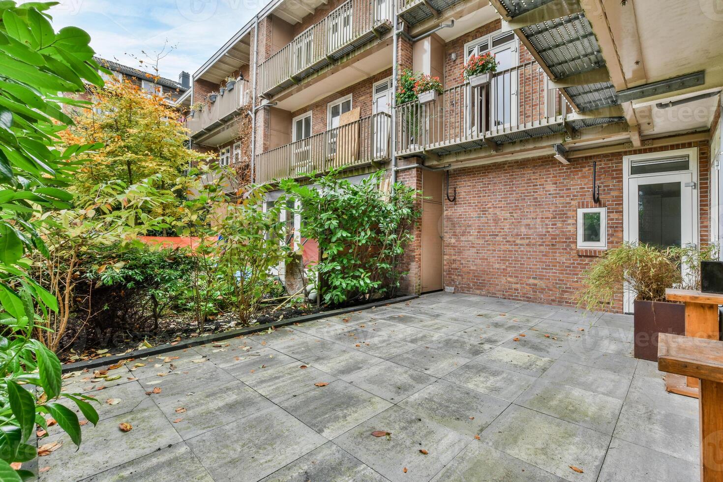 A brick patio with a bench and plants in the yard photo