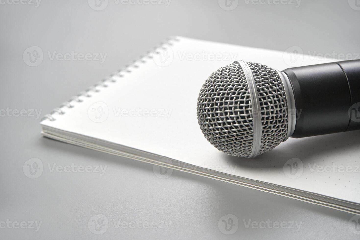Close-up of microphone on notebook. a perfect setup for podcasting, interviews, and creative audio projects. Podcast record. Grey monochrome. Audiobook technology. Home school teaching. Edit episode photo