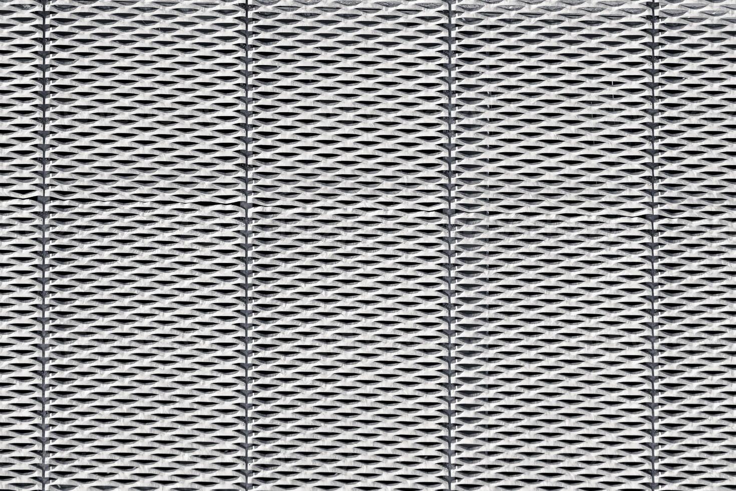Steel surface with a repeated, geometric pattern of perforations resembling small, elongated diamond shapes. photo