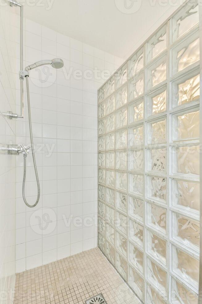 A shower with a glass block wall and a shower head photo