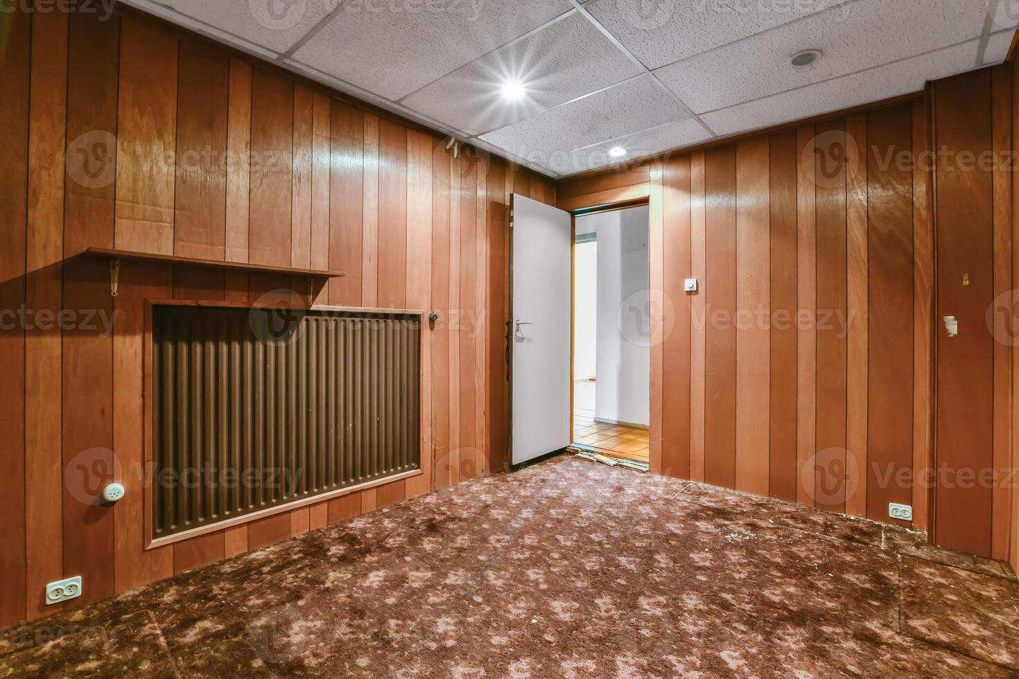 An empty room with wood paneling and a heater photo