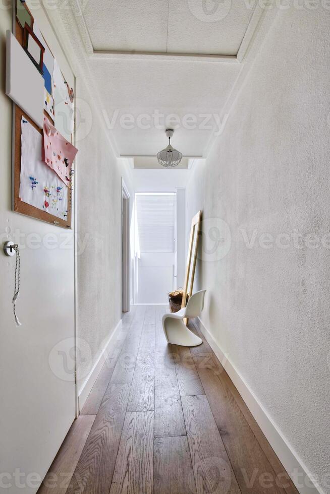 A hallway with a white wall and wooden floor photo