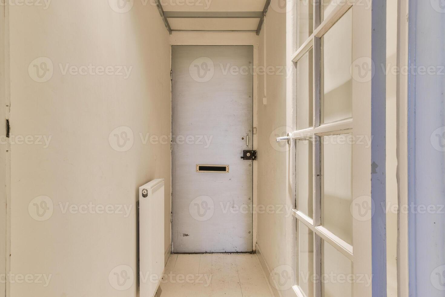A narrow hallway with a door and a window photo