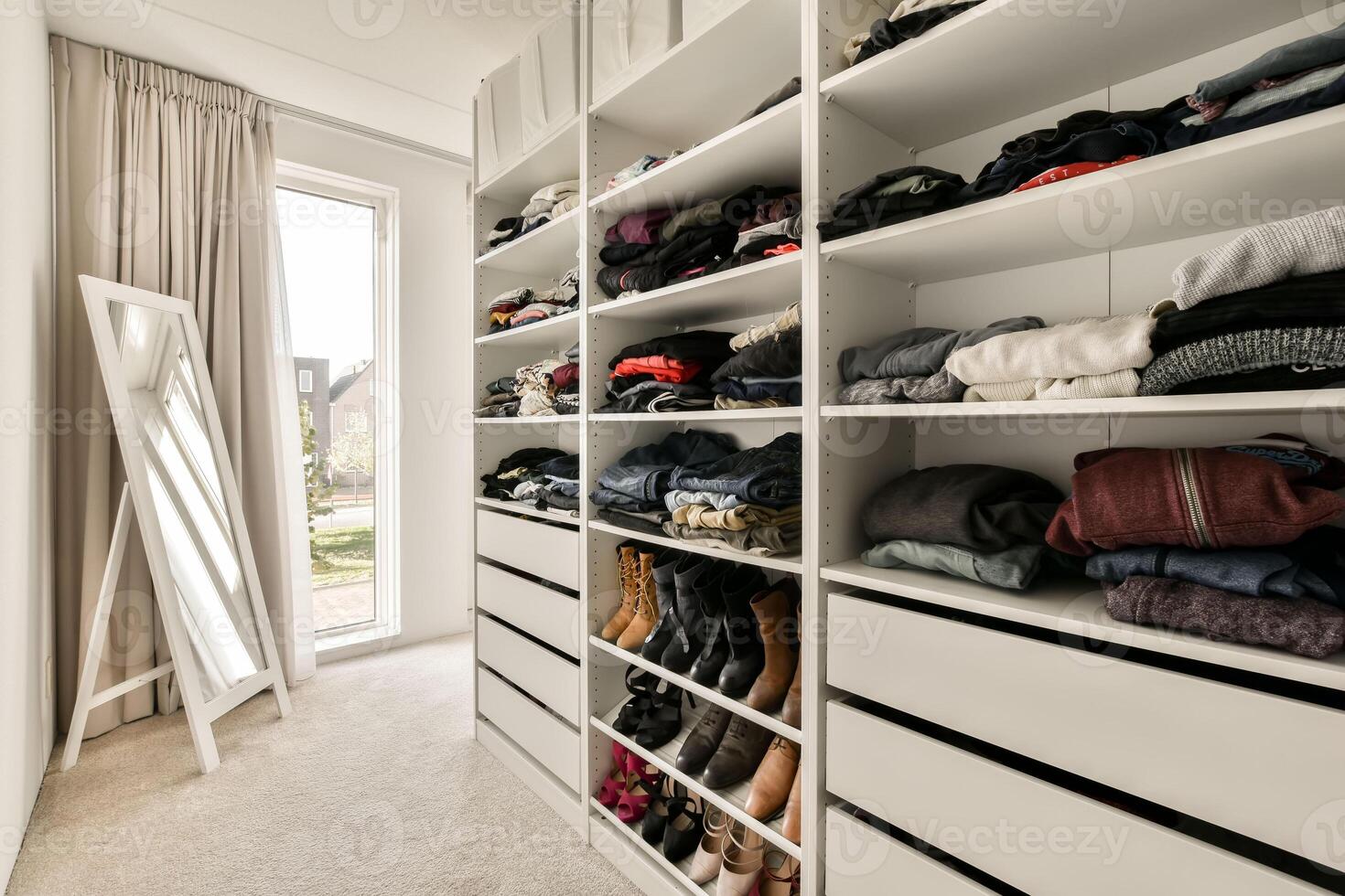 A walk in closet with clothes and shoes photo