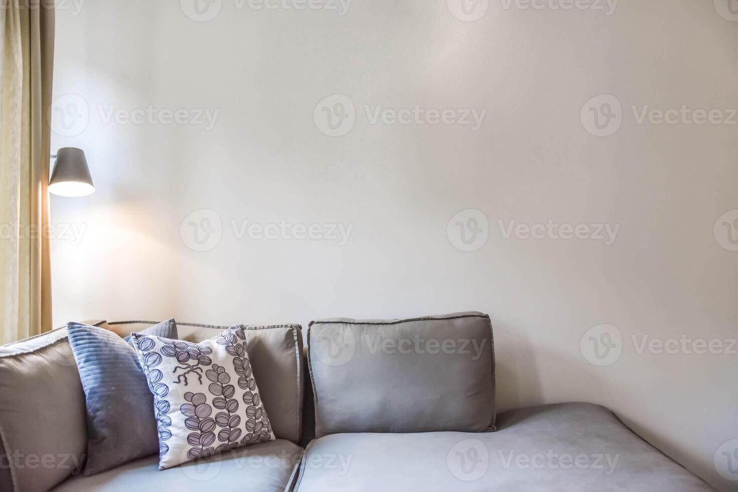 A couch with pillows and a lamp in a room photo