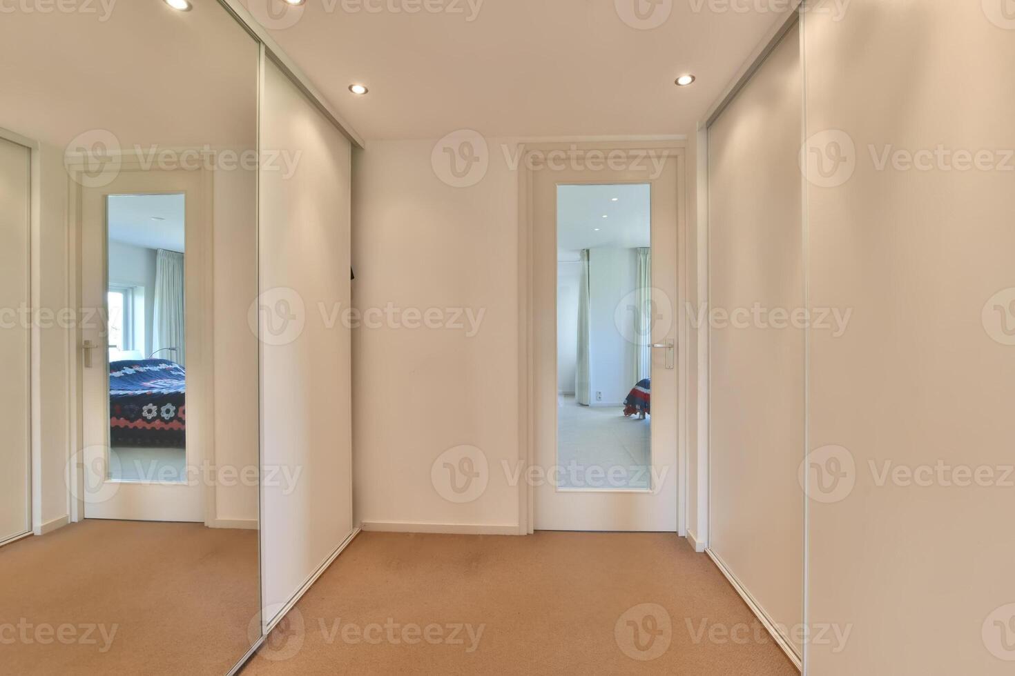 A hallway with a mirror and a bed photo