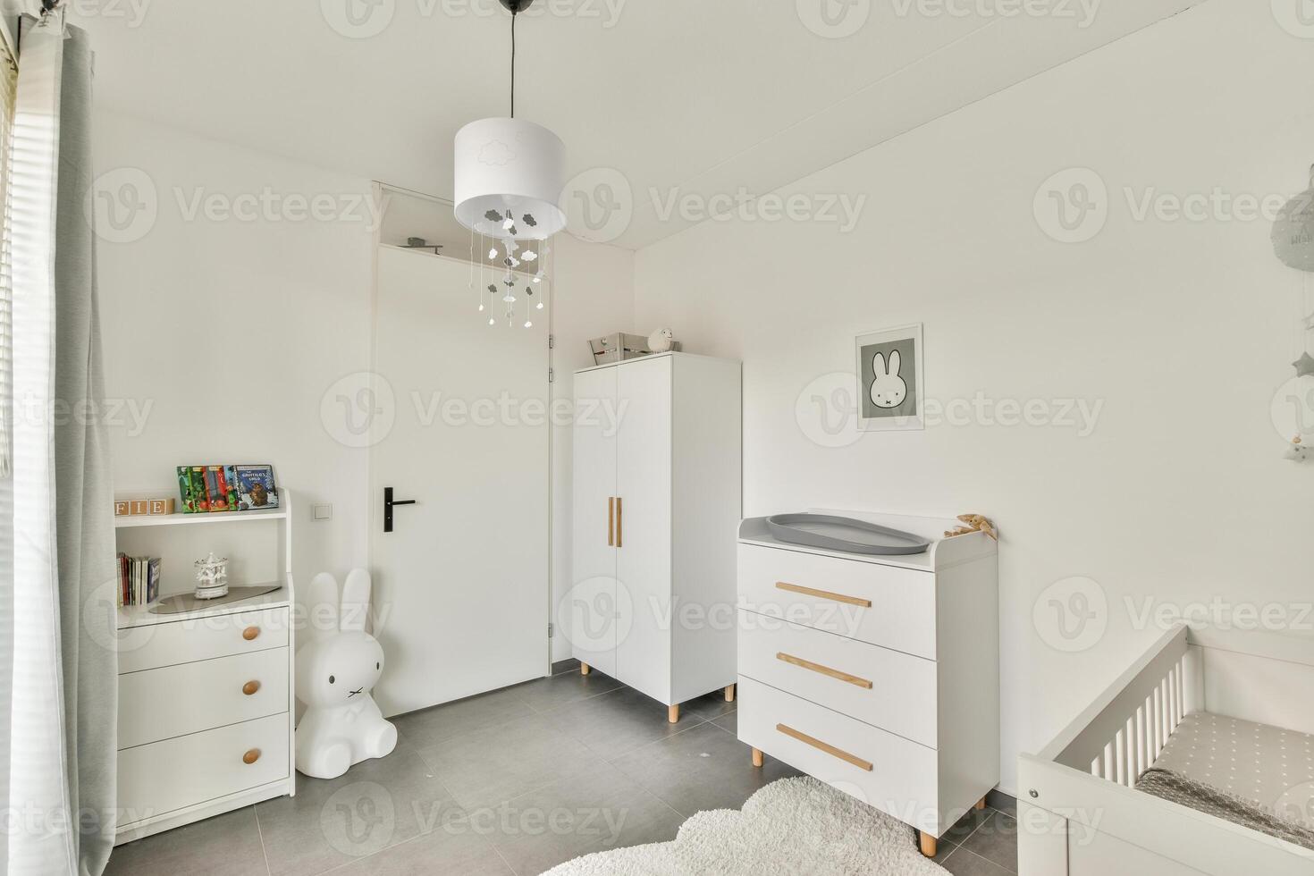 A white nursery room with a crib, dresser and a white dresser photo