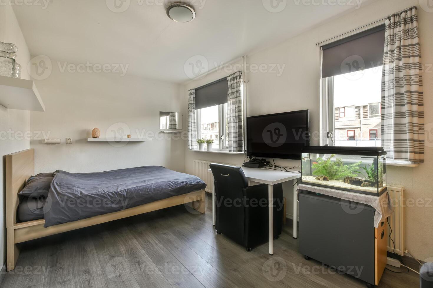 A bedroom with a bed, desk and fish tank photo